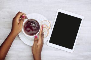 Imagem de uma pessoa com um tablet e um café.